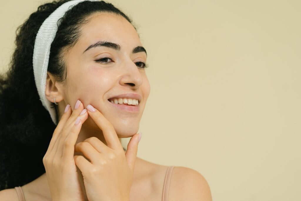 How To Get Rid Of Texture On Skin? Close-up of a smiling woman applying skin treatment, promoting natural beauty and skincare.