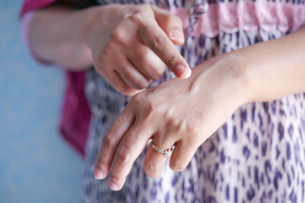 What Causes Dry Skin on Hands? 4 Big Reasons A woman applies skincare cream on her hand, highlighting moisturizing routine.