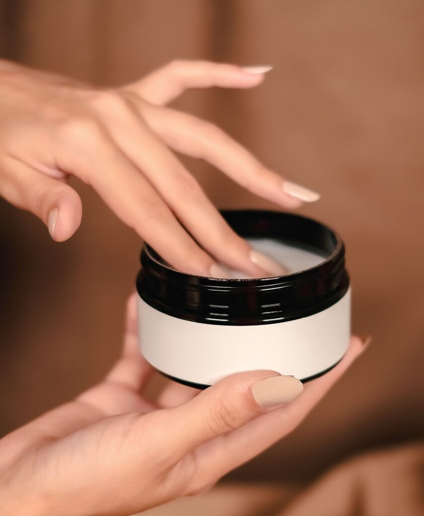 Why Are My Hands So Dry Even When I Moisturize? Here’s 4 Reasons Close-up of hands applying cream from jar, symbolizing skincare and self-care.
