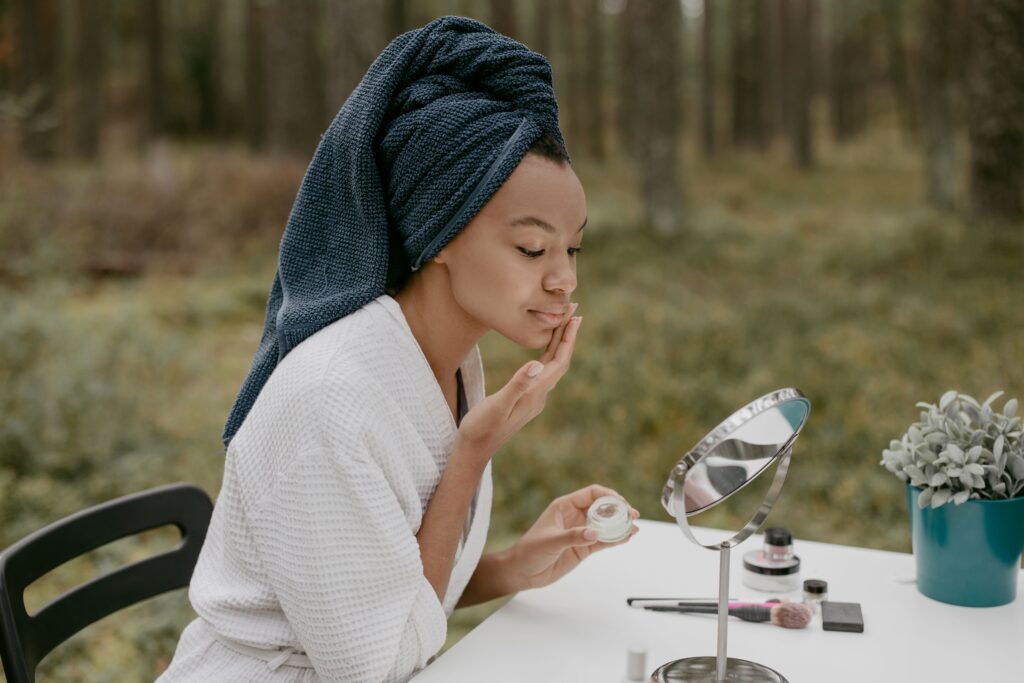 pexels photo 6635915 6635915 A woman in a bathrobe applies face cream in a serene outdoor environment.