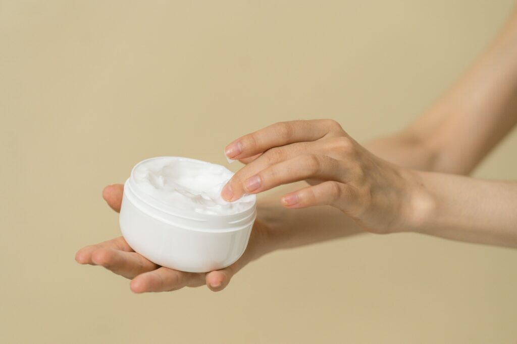 Is Hand Cream the Same as Lotion? What Dermatologist Says!!! Close-up of female hands applying moisturizer from an open jar, highlighting skincare and self-care routine.