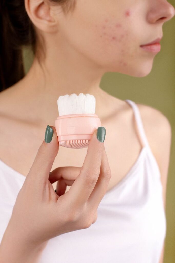 Does Tretinoin Help With Hormonal Acne? Close-up of a woman using a facial brush to care for acne-prone skin.