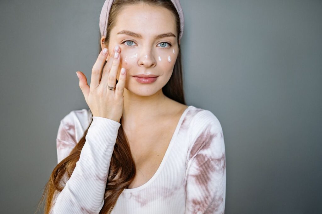 Can Hyaluronic Acid Cause Breakouts? A young woman applies skincare cream to her face, promoting beauty and skincare routine.