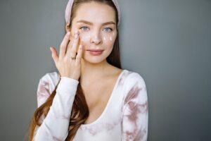 Can Hyaluronic Acid Cause Breakouts? A young woman applies skincare cream to her face, promoting beauty and skincare routine.