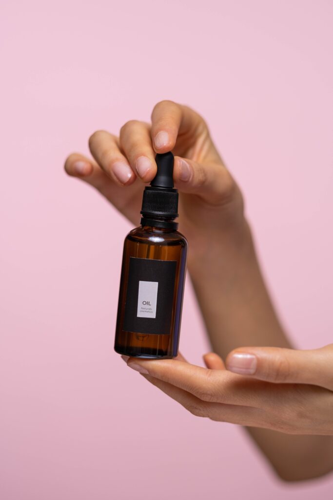Close-up of hands holding a brown dropper bottle of natural face serum, showcasing healthy skin care products.